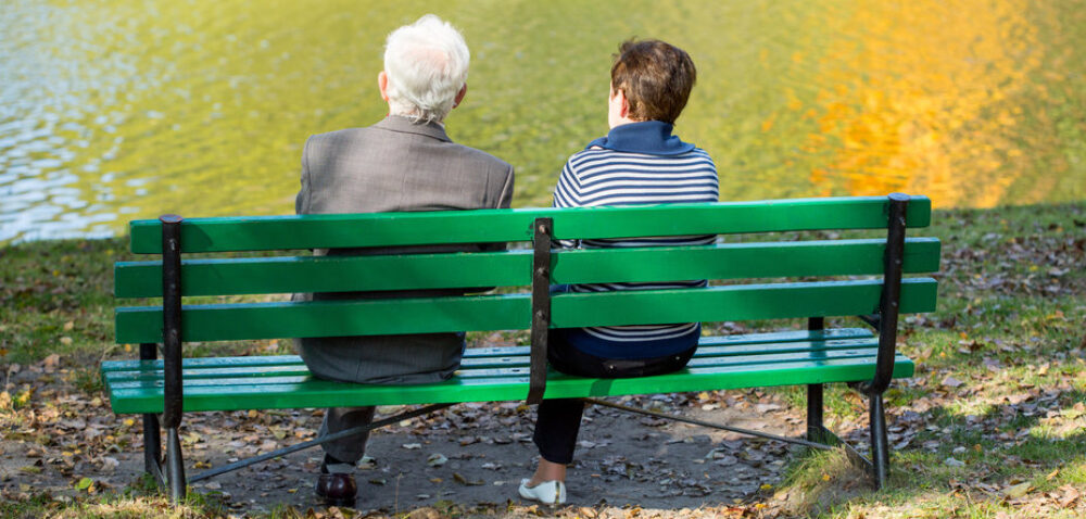 Back of senior couple sitting at the lake